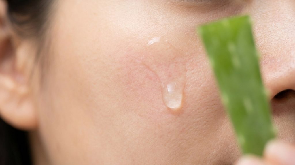 Gros plan sur une goutte de gel d'aloe vera appliquée sur la joue d'une personne présentant des rougeurs.