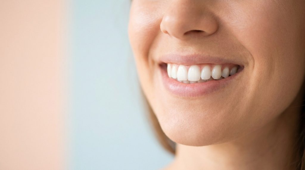Gros plan sur le bas du visage d'une femme souriante montrant ses dents.