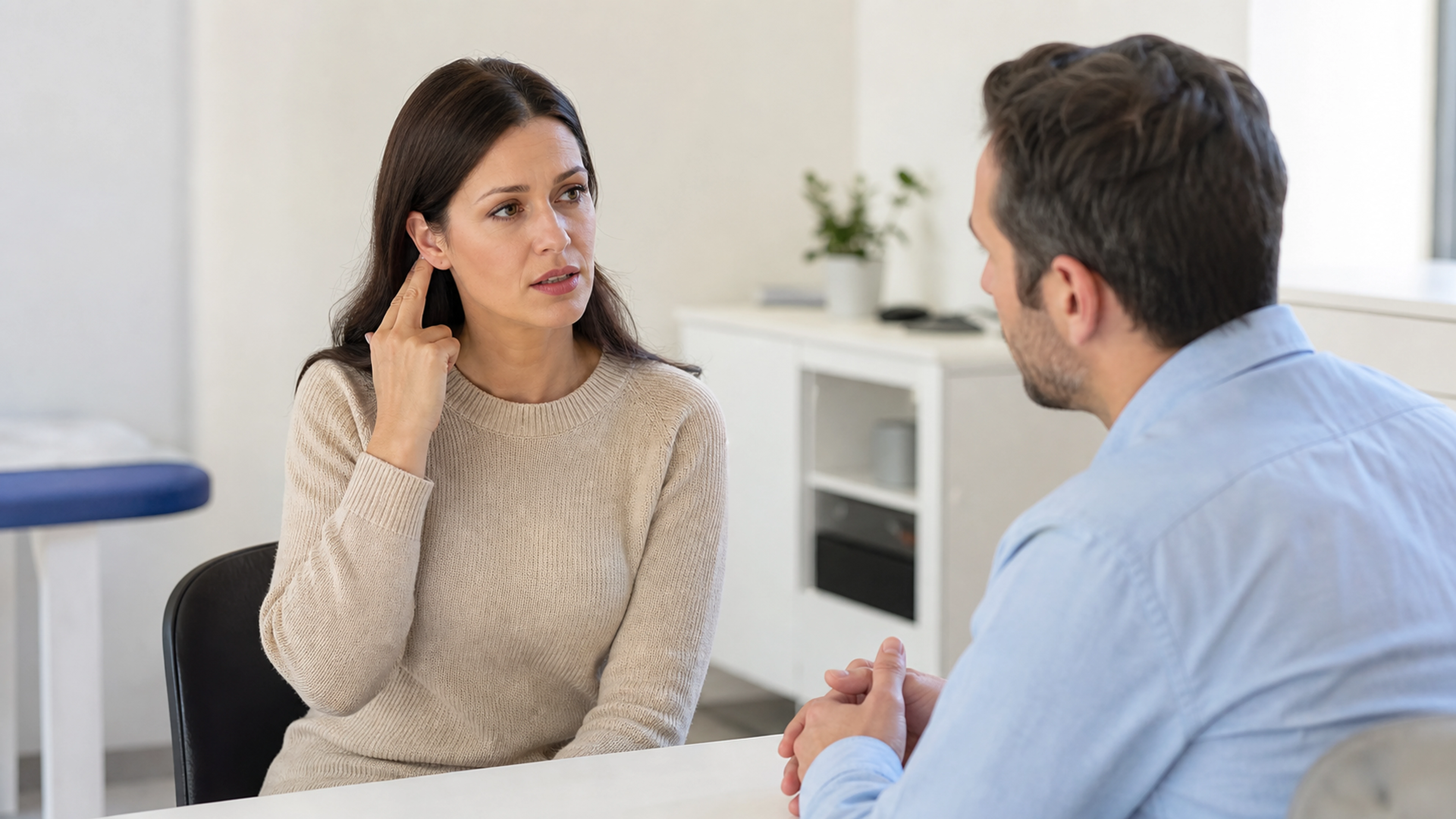 Une patiente évoque une gêne auditive avec un médecin dans un cabinet lumineux.
