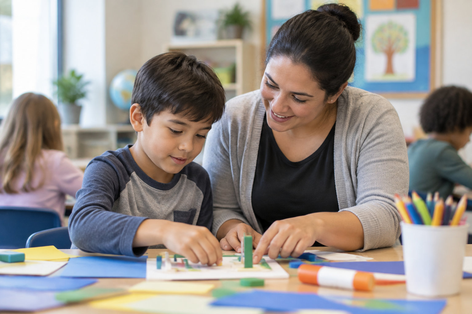 Une enseignante accompagne un garçon dans une activité avec des formes colorées, tandis que d’autres enfants travaillent en arrière-plan.